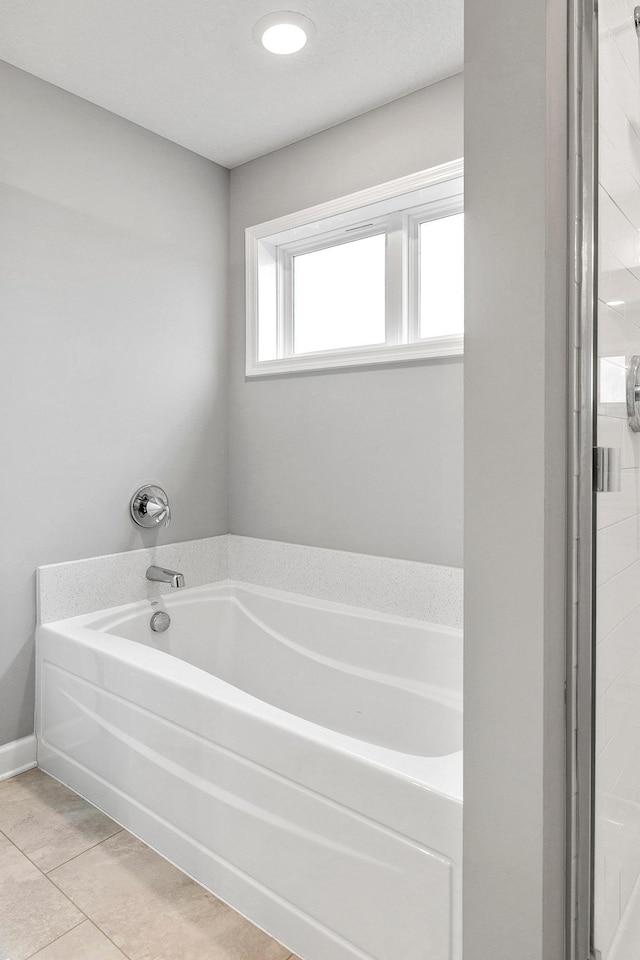 bathroom with tile patterned floors and a bath