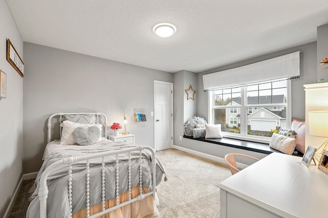 carpeted bedroom featuring a textured ceiling and baseboards