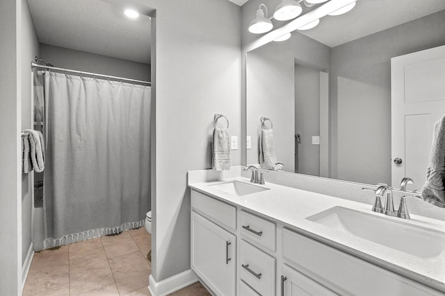 bathroom with a sink, baseboards, toilet, and double vanity