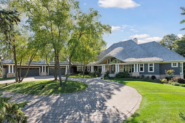 view of front of house featuring curved driveway, a chimney, a front lawn, and stone siding