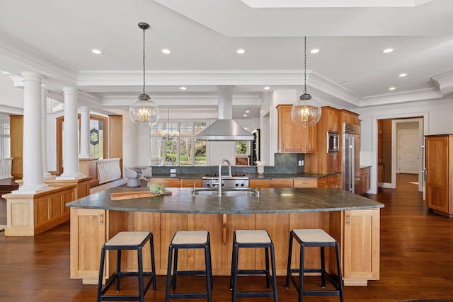 kitchen featuring a kitchen bar, ornate columns, dark wood-type flooring, island exhaust hood, and a sink