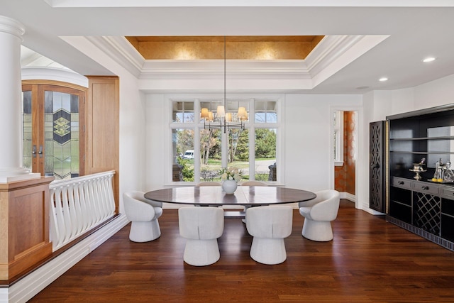 dining room featuring a tray ceiling, an inviting chandelier, ornamental molding, and dark wood-type flooring