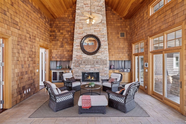 living room with an outdoor stone fireplace, wood ceiling, and high vaulted ceiling