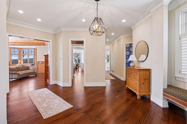 foyer entrance with dark wood-type flooring, baseboards, crown molding, and a chandelier