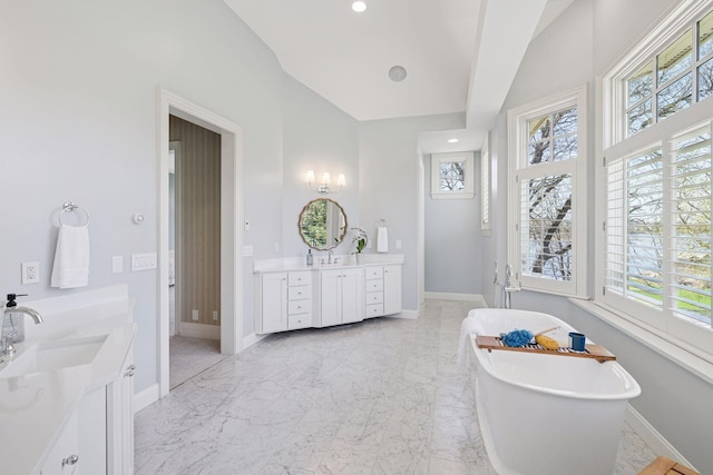 full bathroom featuring a sink, baseboards, a soaking tub, and two vanities