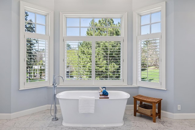 full bath with baseboards, marble finish floor, and a freestanding bath