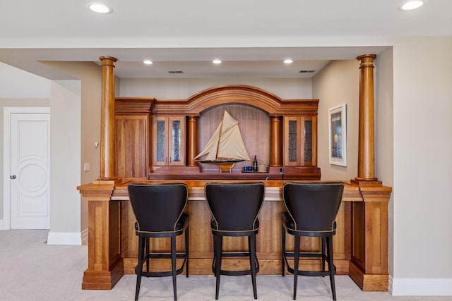 bar with bar area, decorative columns, recessed lighting, and light colored carpet