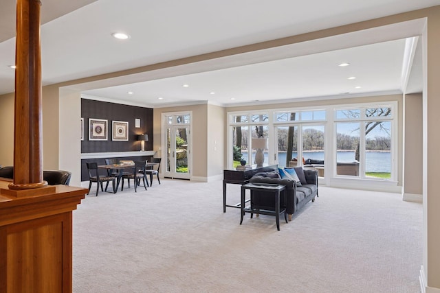 living area featuring crown molding, light colored carpet, recessed lighting, baseboards, and a water view