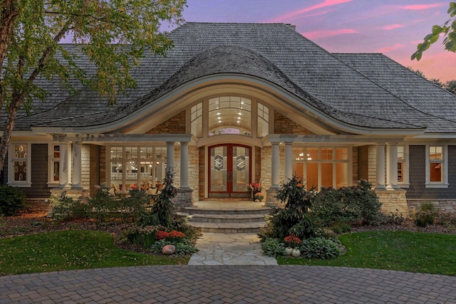 exterior entry at dusk with french doors and stone siding