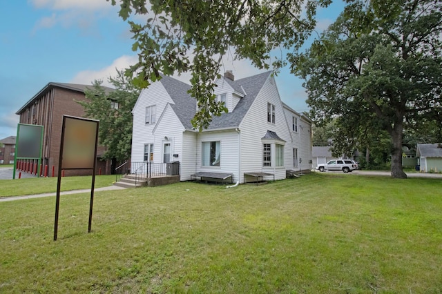 rear view of house featuring a yard and a shingled roof