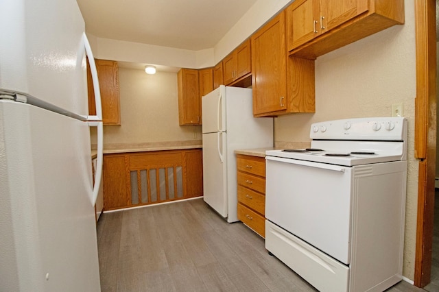 kitchen with light wood-style flooring, light countertops, brown cabinetry, and white appliances