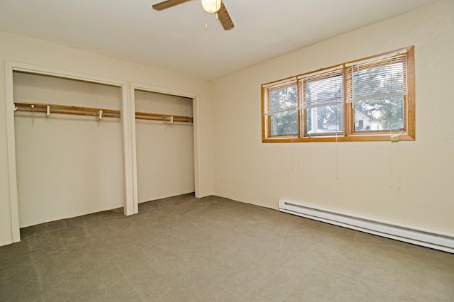 unfurnished bedroom with dark colored carpet, a baseboard heating unit, multiple closets, and ceiling fan