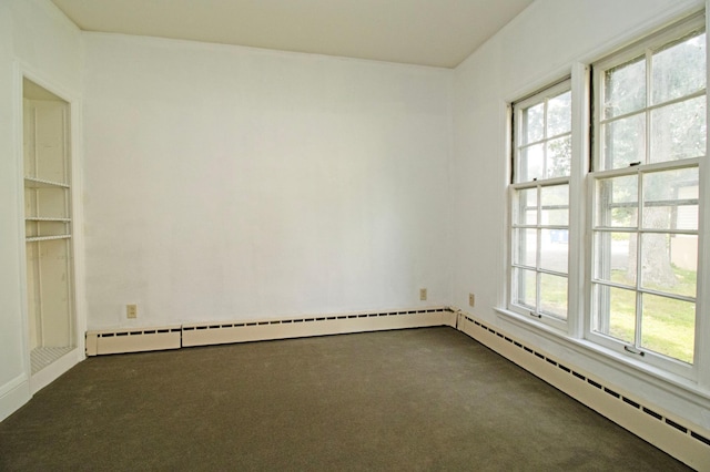 spare room with a baseboard radiator and dark colored carpet