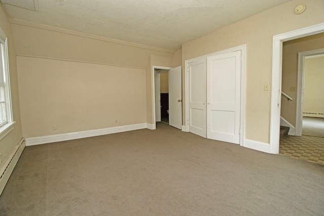 unfurnished bedroom featuring a closet, baseboards, carpet flooring, and a baseboard heating unit