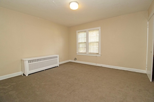 unfurnished room with radiator heating unit, dark colored carpet, and baseboards