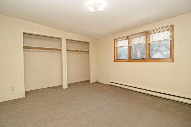 unfurnished bedroom with a baseboard radiator, two closets, and carpet floors