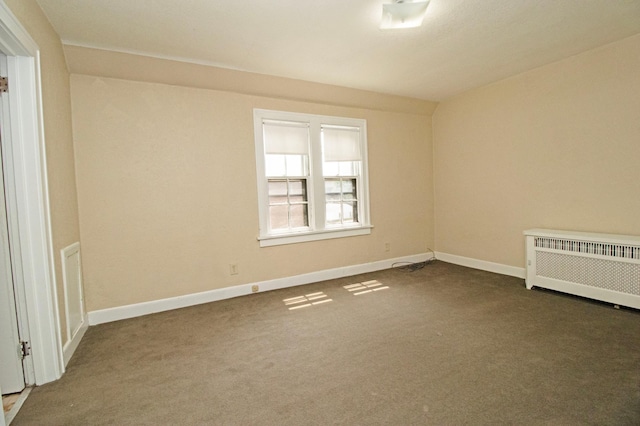unfurnished room featuring dark carpet, radiator, and baseboards