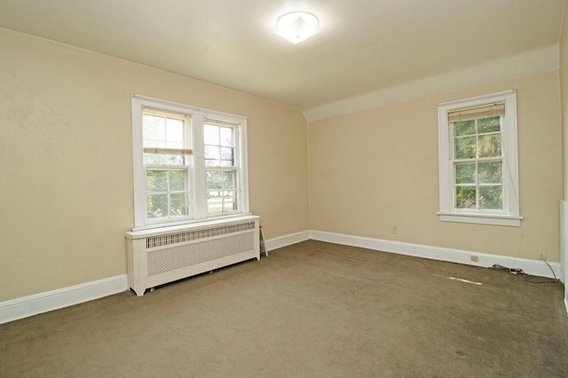 carpeted empty room with baseboards, radiator, and lofted ceiling