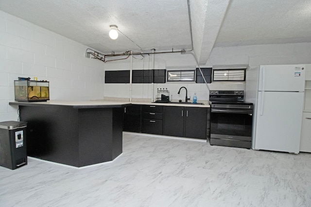 kitchen featuring a sink, light countertops, freestanding refrigerator, stainless steel electric stove, and dark cabinets
