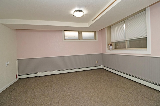 basement featuring dark carpet, wainscoting, and baseboard heating