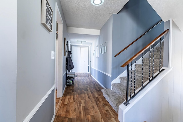 hall featuring a textured ceiling, wood finished floors, and stairs
