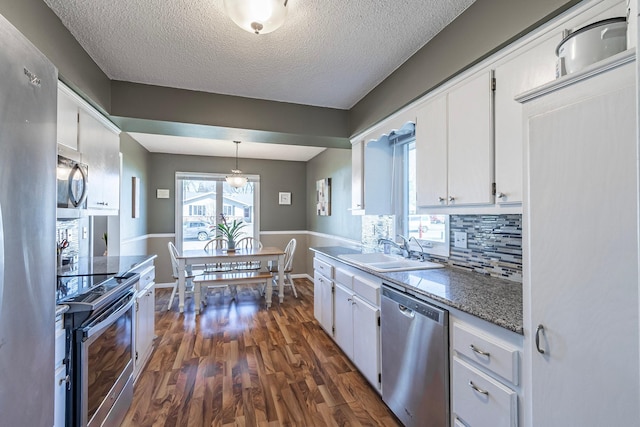 kitchen with tasteful backsplash, white cabinetry, appliances with stainless steel finishes, dark wood-style flooring, and a sink