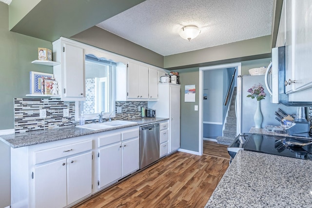kitchen featuring tasteful backsplash, white cabinets, dishwasher, a sink, and dark wood finished floors