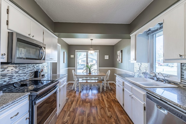 kitchen featuring dark wood finished floors, white cabinetry, appliances with stainless steel finishes, a sink, and backsplash