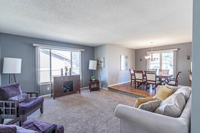 carpeted living room featuring baseboards, an inviting chandelier, and a textured ceiling
