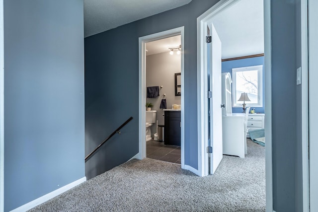 corridor featuring carpet flooring, an upstairs landing, and baseboards