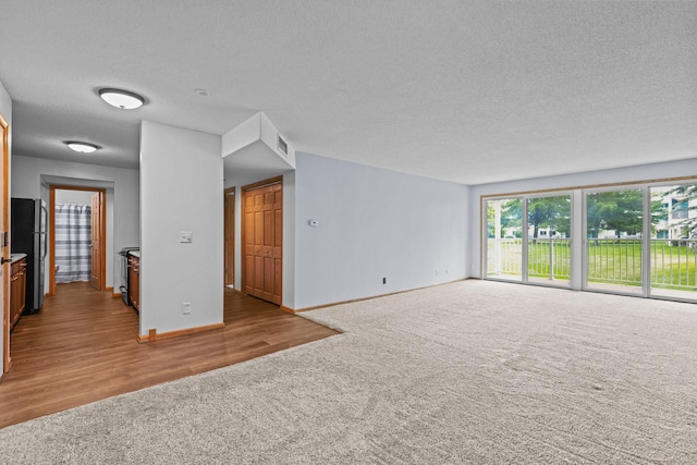 120 Demont Ave E Unit 103, Little Canada, MN 55117 - unfurnished living room with carpet floors, a textured ceiling, and wood finished floors