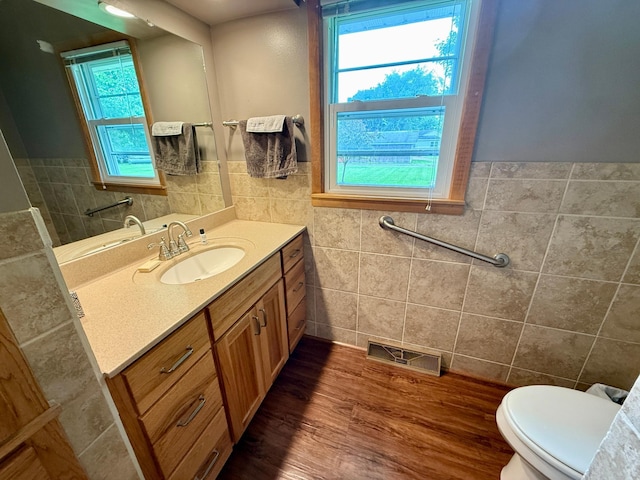 603 Maple Ave, Olivia, MN 56277 - half bathroom with tile walls, vanity, healthy amount of natural light, wood finished floors, and a wainscoted wall