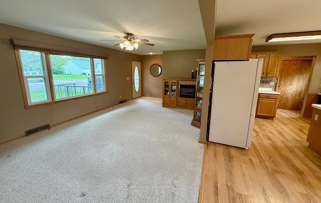 603 Maple Ave, Olivia, MN 56277 - kitchen with freestanding refrigerator, a ceiling fan, brown cabinetry, light wood-type flooring, and light countertops
