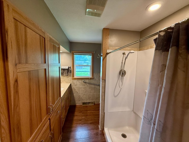 603 Maple Ave, Olivia, MN 56277 - full bathroom with tile walls, a shower with curtain, wood finished floors, wainscoting, and vanity
