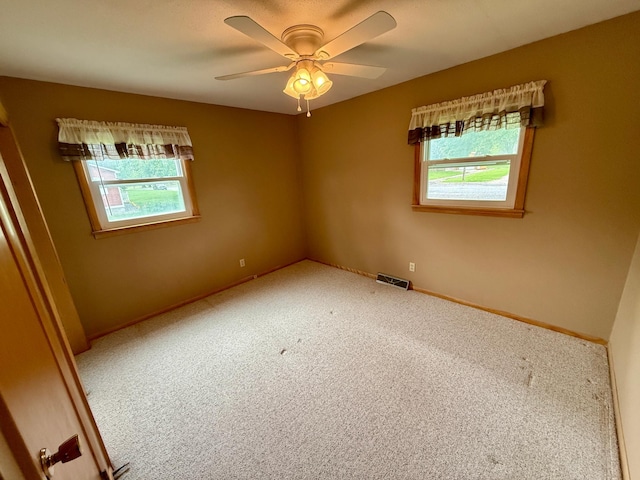 603 Maple Ave, Olivia, MN 56277 - empty room featuring healthy amount of natural light, carpet, and a ceiling fan