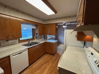 kitchen with range, light countertops, white dishwasher, and brown cabinets