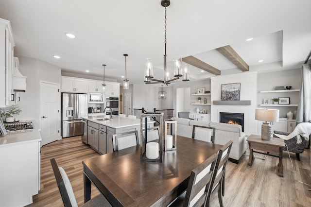 548 Mallard St NE, Hanover, MN 55341 - dining space featuring light wood-style flooring, recessed lighting, a lit fireplace, a chandelier, and beam ceiling