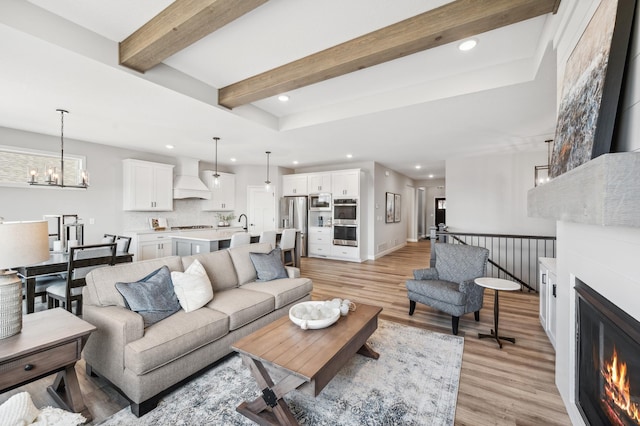 548 Mallard St NE, Hanover, MN 55341 - living room featuring light wood-type flooring, recessed lighting, a fireplace, beamed ceiling, and a chandelier