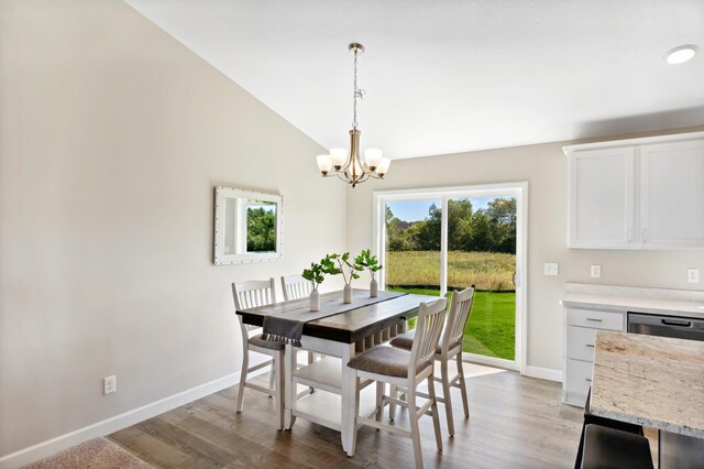 dining room featuring a chandelier, vaulted ceiling, wood finished floors, and baseboards