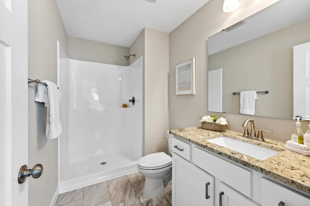full bathroom with visible vents, toilet, vanity, baseboards, and walk in shower