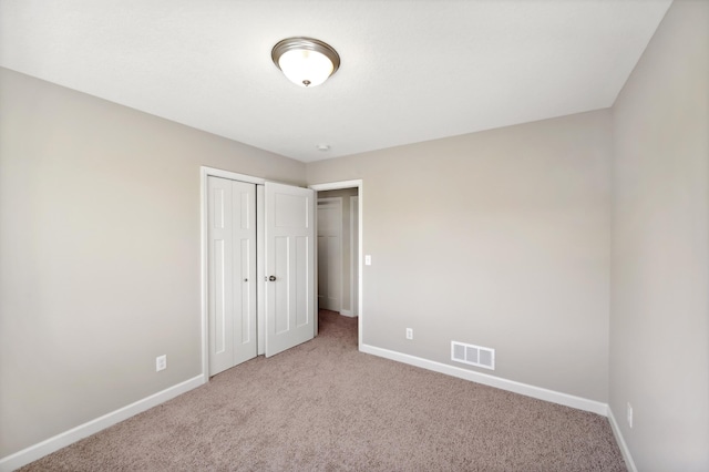 unfurnished bedroom featuring visible vents, baseboards, a closet, and carpet