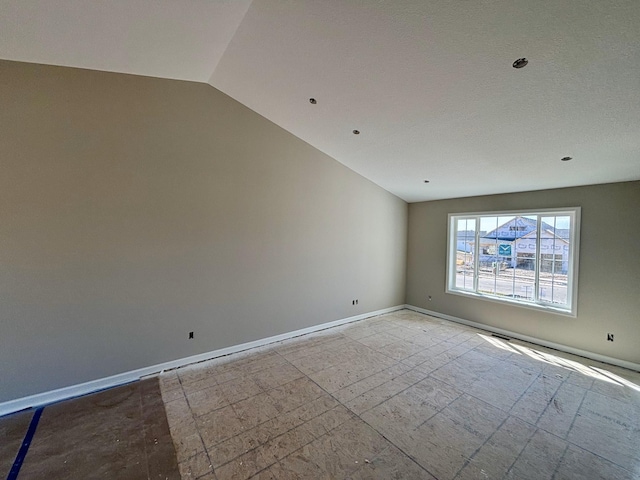 unfurnished room featuring lofted ceiling and baseboards