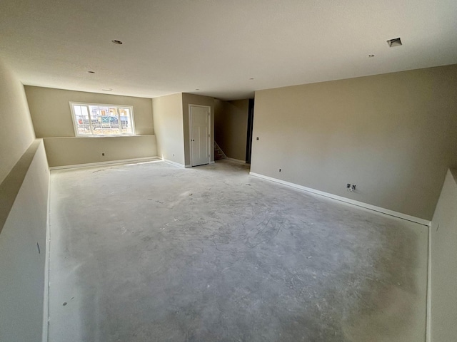 unfurnished room featuring concrete flooring, baseboards, and stairs