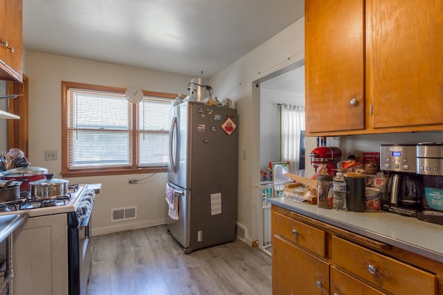 kitchen featuring plenty of natural light, light wood-style floors, gas stove, visible vents, and freestanding refrigerator