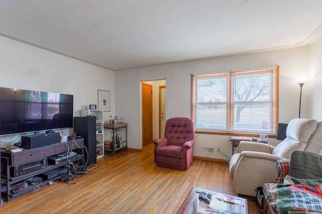 living room with wood finished floors, visible vents, and baseboards