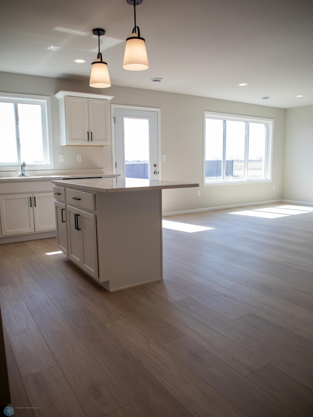 861 2nd Ave, Horace, ND 58047 - kitchen with light wood-type flooring, white cabinetry, decorative light fixtures, a center island, and open floor plan