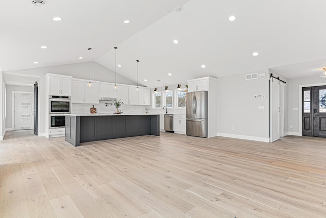 kitchen featuring white cabinets, visible vents, a barn door, appliances with stainless steel finishes, and decorative backsplash