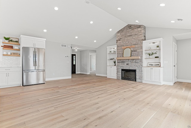 unfurnished living room featuring light wood-style floors, a fireplace, vaulted ceiling, visible vents, and baseboards