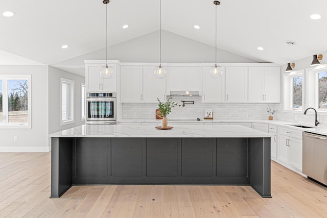 kitchen featuring a sink, a wealth of natural light, appliances with stainless steel finishes, white cabinetry, and vaulted ceiling