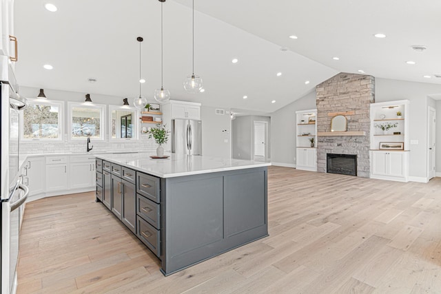 kitchen with a center island, freestanding refrigerator, white cabinetry, gray cabinetry, and light wood-style floors